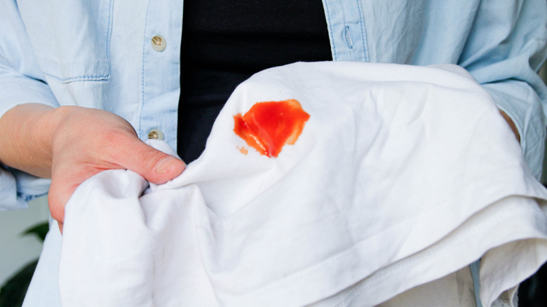 A ketchup stain is plainly visible on a white t-shirt.