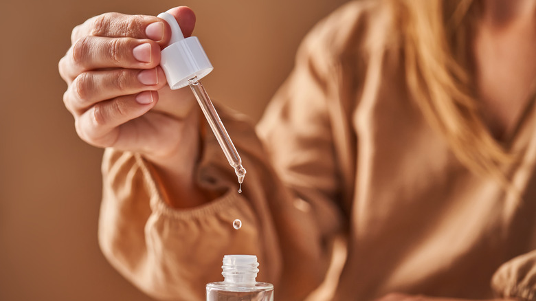 A pipette of clear solution is being drawn from a small bottle.