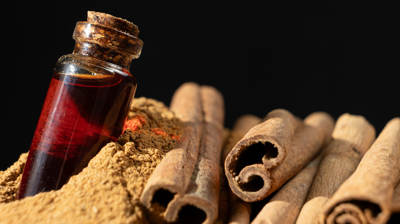A bottle of oil next to cinnamon sticks