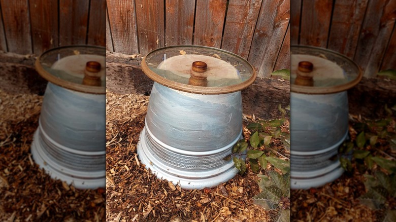 DIY birdbath made from old pot lid in backyard.