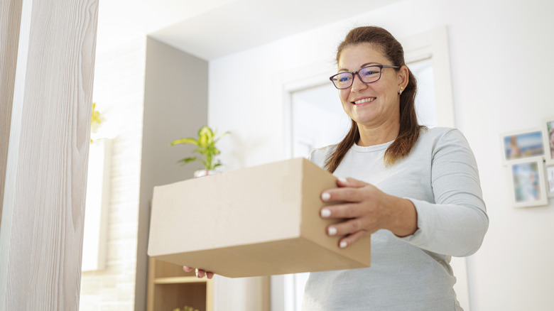 A woman smiles as she holds a shoebox
