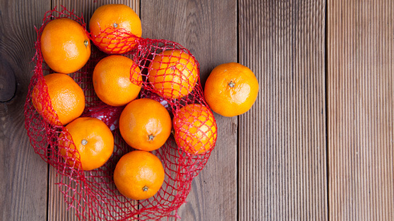 Pile of clementine fruits in red mesh produce netting