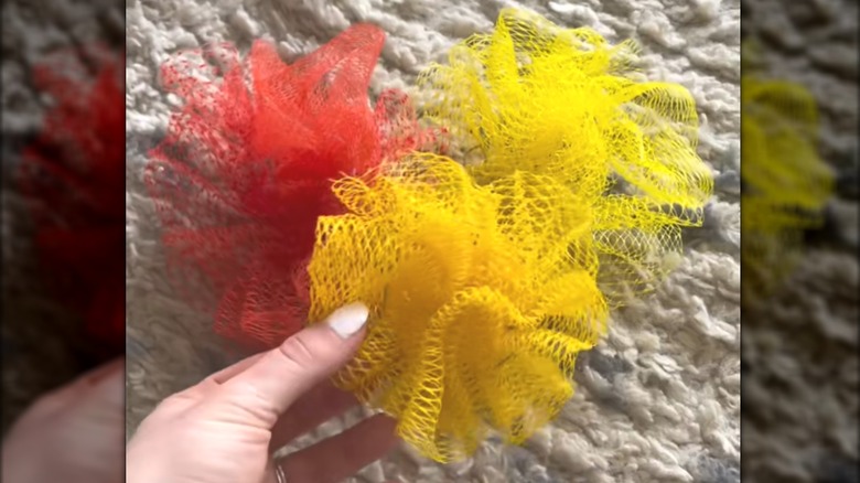 Three DIY red-orange and yellow loofahs over plush carpet