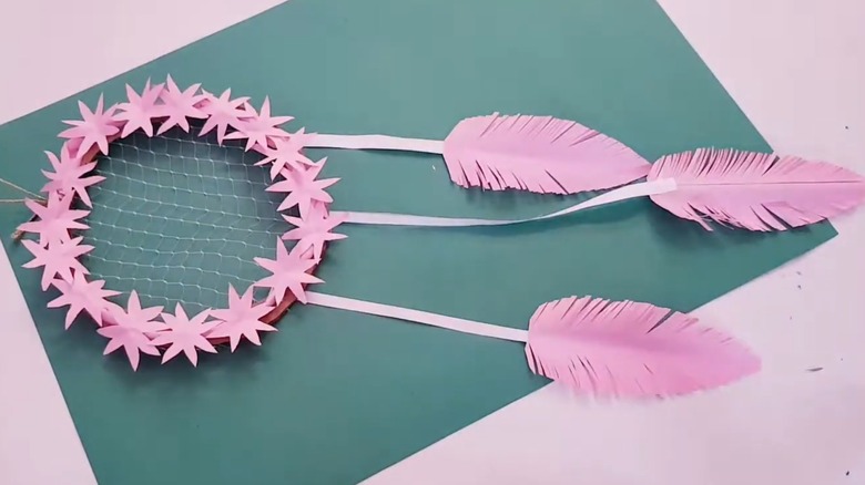 Pink homemade dreamcatcher with paper accents and net center
