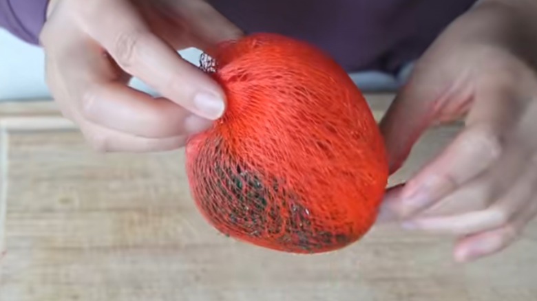 Clump of produce bags combined to form orange household scrubber