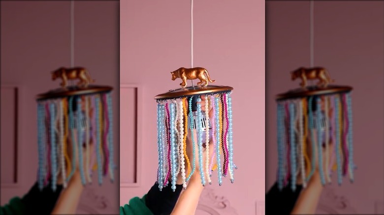 A chandelier DIYed from a metal pot lid, paint, and beads with a pendant light.