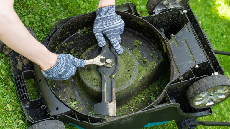 Person removing an old worn blade from their lawn mower
