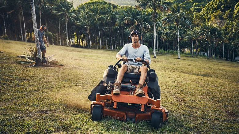 Worker cutting the grass with a riding mower