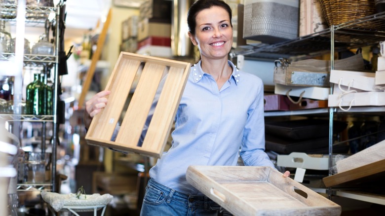 Smiling woman holding wood trays in a thrift store