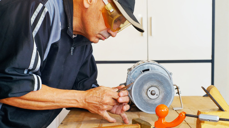 Man using a bench grinder to sharpen a tool