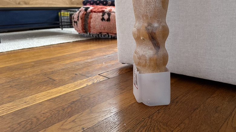 A plastic milk carton bottom as a DIY furniture slider on a wooden table leg