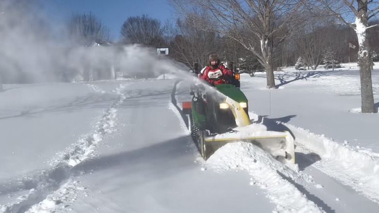Homeowner removing snow from driveway with snow blower tractor attachment