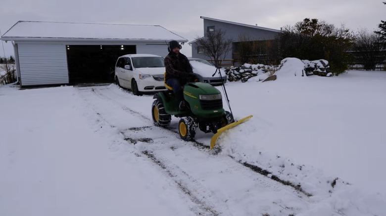 Man removing snow from driveway with rider mower