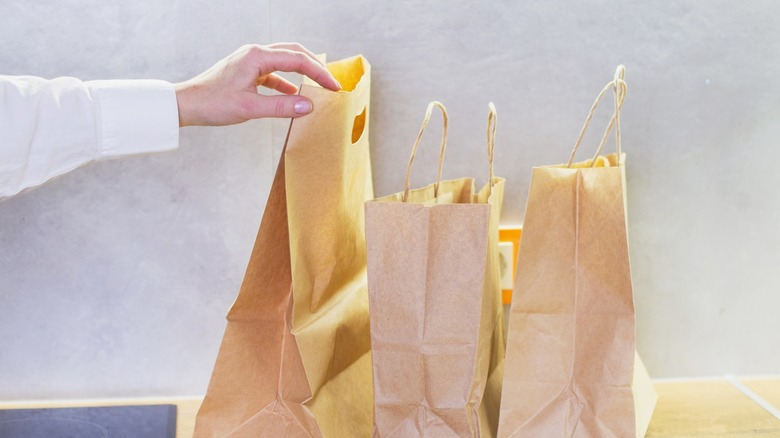 Person's hand reaching for brown paper bags