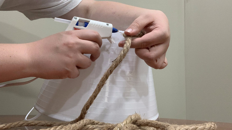 hands gluing rope onto bucket