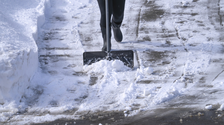 a person uses a snow shovel on an icy driveway