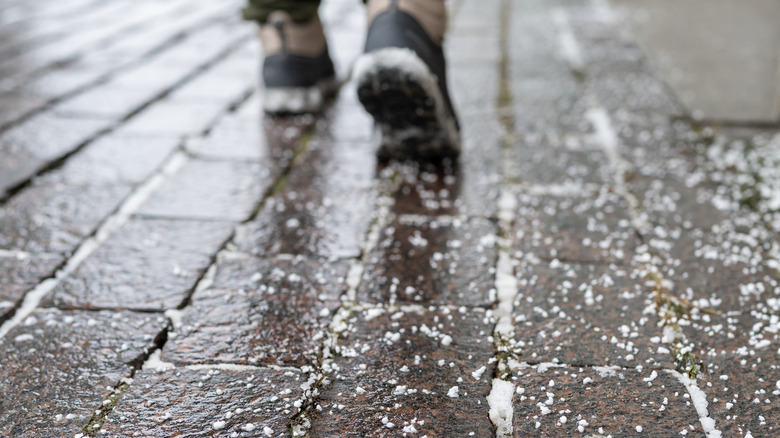 a person wearing boots walks over a salted driveway
