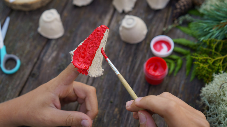 Hands painting the raised cones of an egg carton red