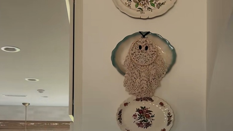 A lace doily ghost mounted on top of a platter displayed on a wall