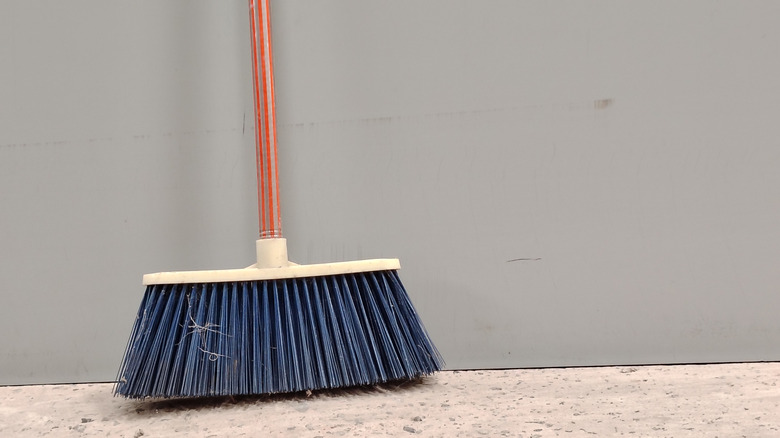 A broom sitting against a gray wall