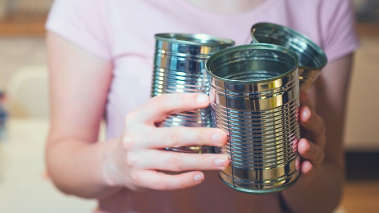Woman holding empty tin cans to use for repurposing