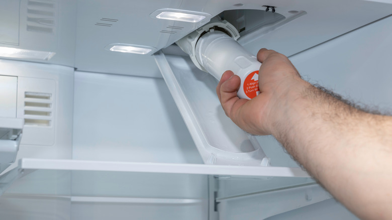 man changing a water filter inside his fridge