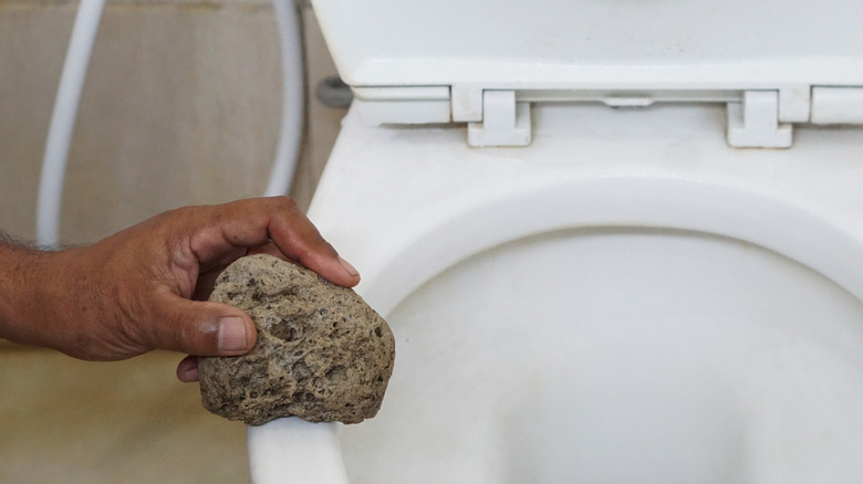 A pumice stone being used to clean a toilet