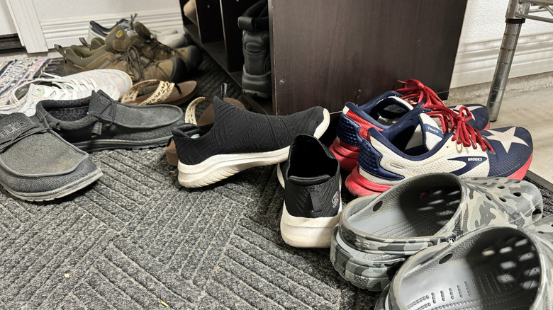 pile of shoes inside a home by the door with ineffective shoe organizer
