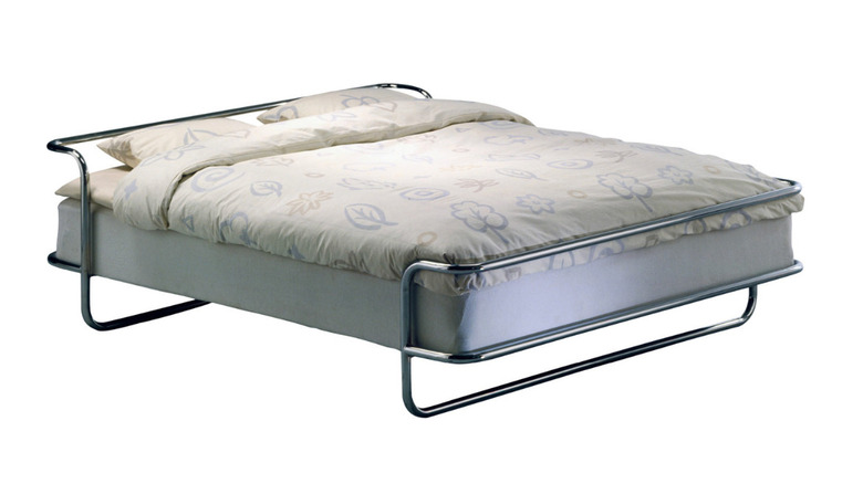 A KROMVIK bed with a retro chrome frame and a patterned duvet.