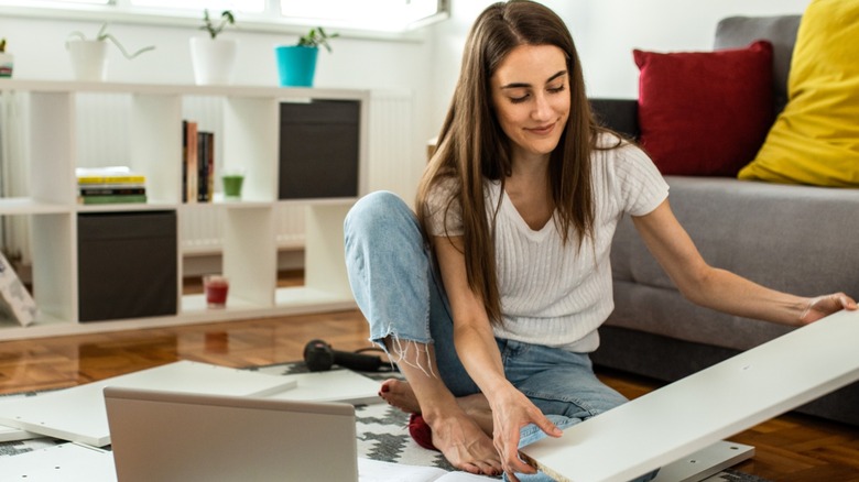 Woman unboxing IKEA cabinet in living room to build DIY side table