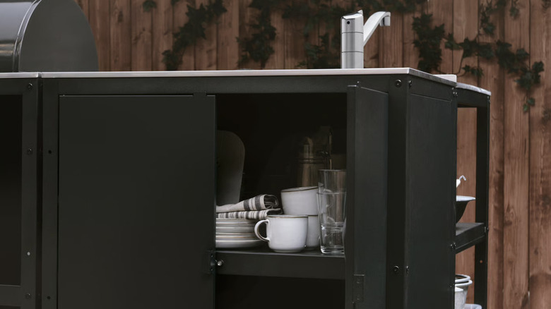 GRILLSKAR outdoor kitchen island unit with stored coffee cups and dishes
