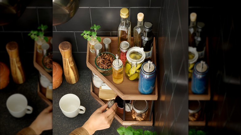 A person's hand reaching for an item on a two-tiered NÅLBLECKA corner shelf from IKEA