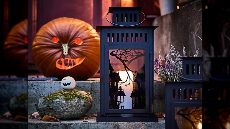 A black haunted landscape lantern with a lit candle inside
