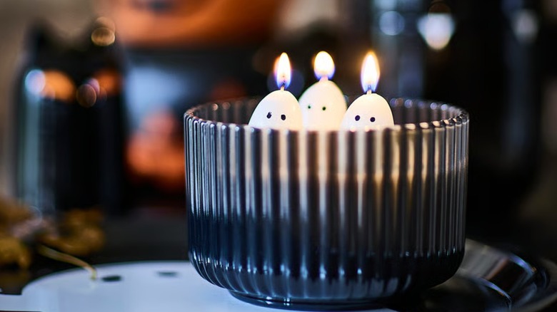 A tinted glass dish with lit ghost candles inside
