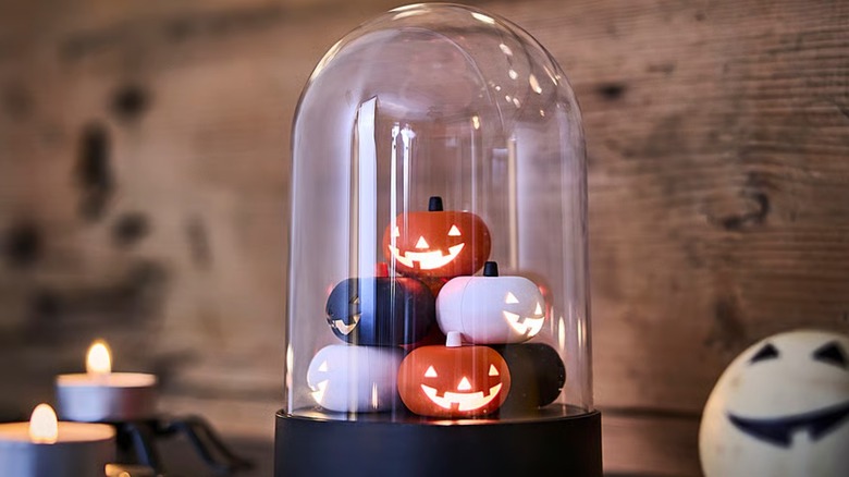A glass decoration with tiny glowing pumpkins inside