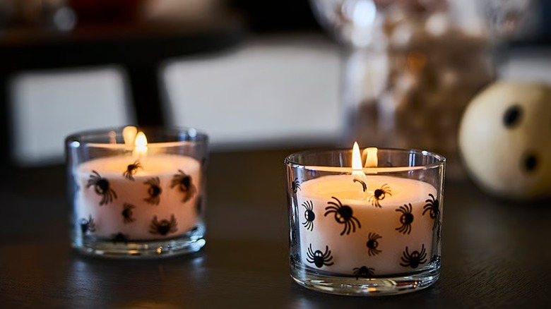 Lit candles in a spider-patterned glass container