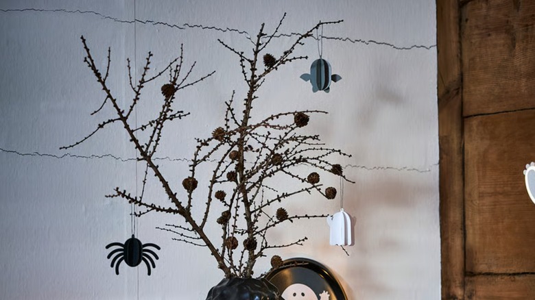 Small paper spider, ghost, and bat hanging from decorative black twigs