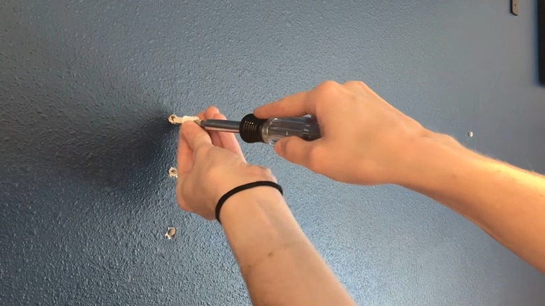 Person installing a drywall anchor to hold a wall-hanging storage unit