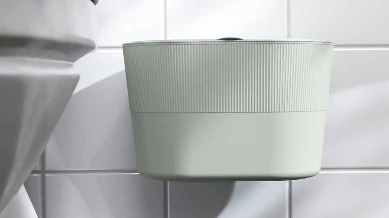 KINNASJÖ trash can mounted on a tile wall beside a toilet