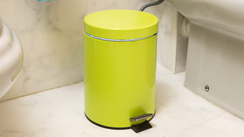Small green bathroom garbage bin beside toilet