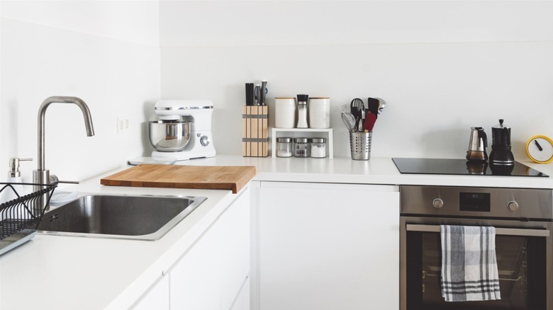 A modern white kitchen with assorted items organized on the counters