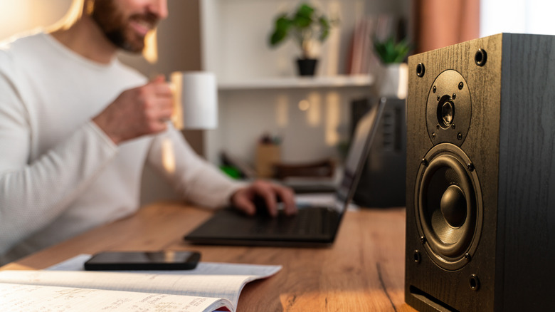 A man working with a speaker next to him on the table