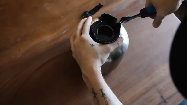 A man with tattoos takes apart an IKEA coffee pot