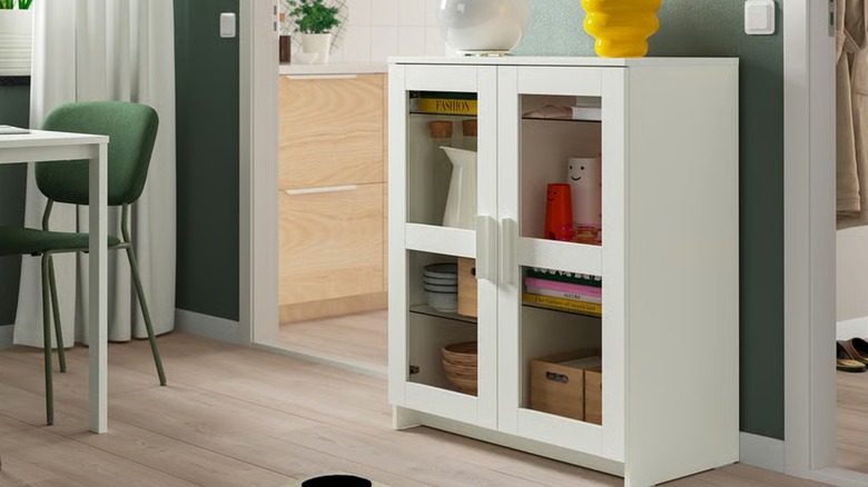 A white cabinet with see-through doors in a living room