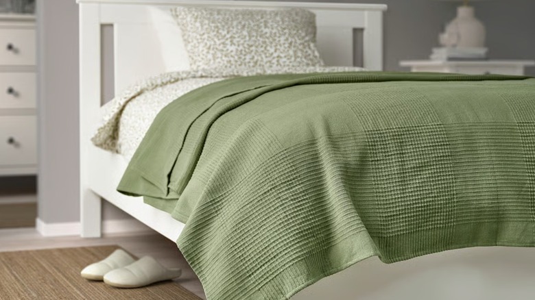 A green bedspread draped on a bed