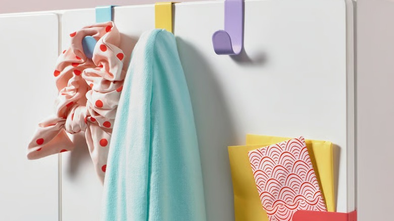 Colorful hooks holding various items against a white surface