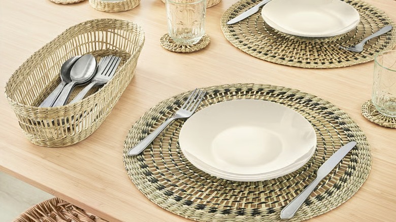 Dinnerware and cutlery placed over woven placemats