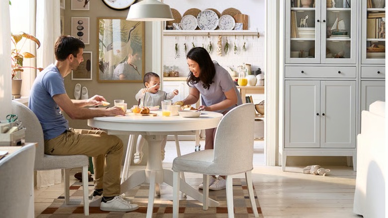 A round, white dining table with a family sitting or standing around it