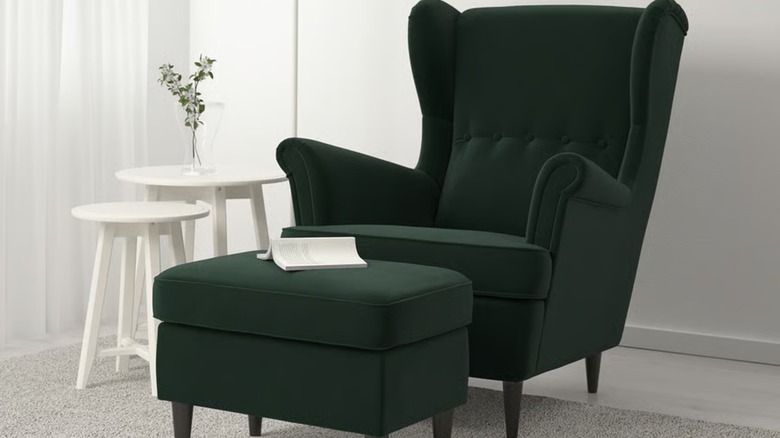 A tufted dark green armchair with a matching ottoman in a living room