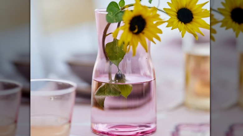 A small pink glass vase with cut sunflowers in it